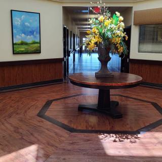 A hallway with a central table displaying a flower arrangement, surrounded by artwork and decor.