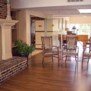 A cozy living room with wooden chairs, a fireplace, and hardwood flooring.