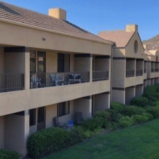 A row of residential apartments with balconies overlooking a lush green area.