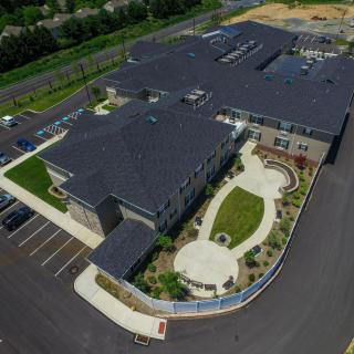 Aerial view of a large commercial building with an adjacent parking lot and landscaped area.