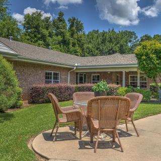 A serene backyard patio with wicker furniture set against a charming house backdrop.