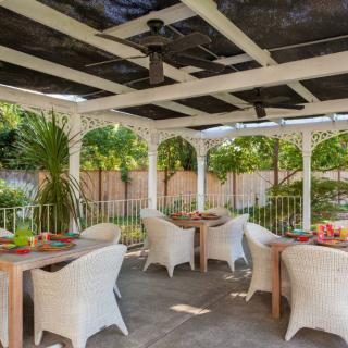 A beautifully set outdoor patio with wicker chairs and tables surrounded by lush greenery.