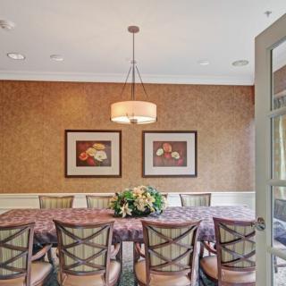 A dining room with a long table and several chairs, featuring a chandelier and framed wall art.