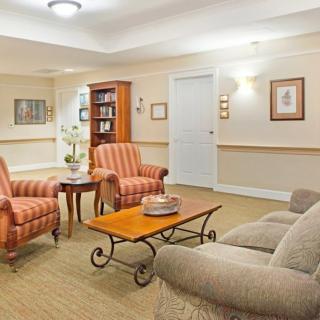 A cozy living room with armchairs, a sofa, and a coffee table surrounded by artwork and a bookshelf.