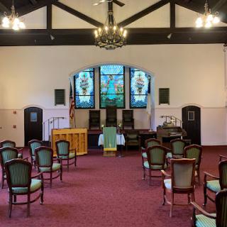 A serene view of a church interior showcasing elegant stained glass windows and arranged seating.