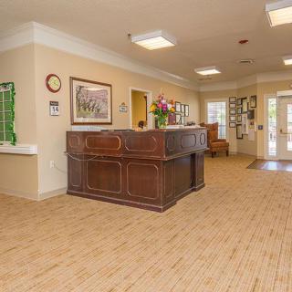 A spacious lobby with a wooden reception desk and decorative elements.