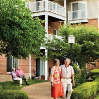 Elderly couples enjoying a walk in a retirement community's garden.