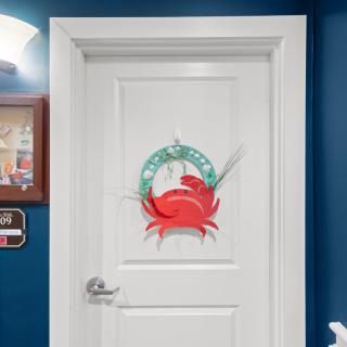 A white door adorned with a vibrant red crab design, set against a blue wall.