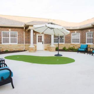 A cozy outdoor patio with comfortable seating and an umbrella, set against a brick building.