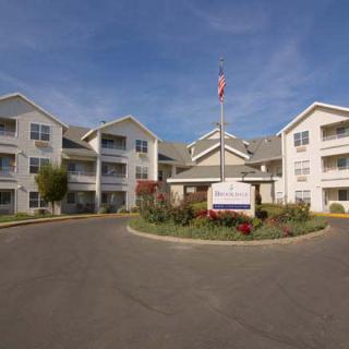 A residential apartment complex with multiple buildings and a circular driveway under a clear blue sky.