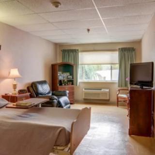A hospital room featuring a bed, medical equipment, and a comfortable chair with natural light coming in through the window.