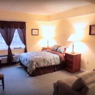 A cozy bedroom with a neatly made bed, side tables with lamps, and a window with curtains.