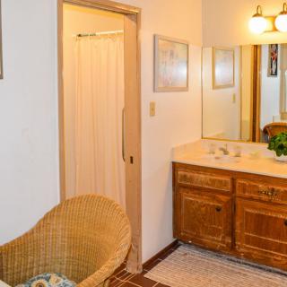 A cozy bathroom with a wooden vanity and wicker chair.
