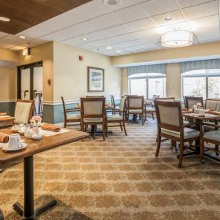 A well-lit dining area with neatly arranged tables and chairs, featuring a cozy interior design.