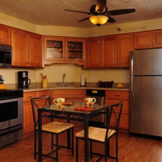 A modern kitchen with wooden cabinets, stainless steel appliances, and a small dining table.