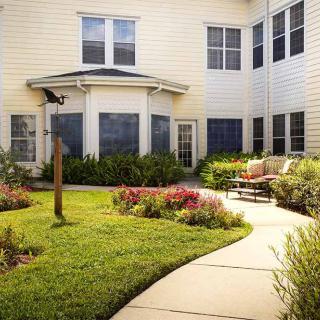 A well-maintained garden with a winding pathway and a bench outside a building.