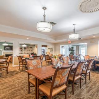 A spacious dining room with neatly arranged tables and chairs, featuring modern lighting and a welcoming atmosphere.