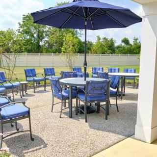 A patio setup with blue cushioned chairs and a large umbrella, perfect for outdoor gatherings.