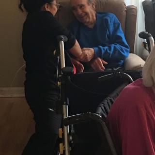 A caregiver interacting with an elderly person in a wheelchair.