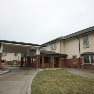 A two-story residential building with a covered entrance and driveway.
