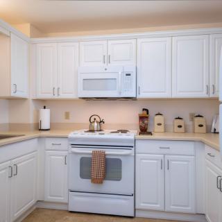 A modern kitchen with white cabinets and appliances.