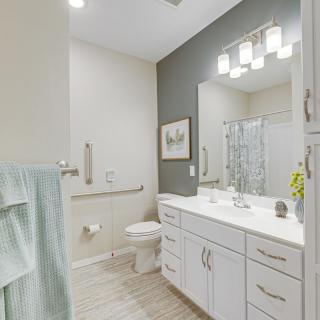 A modern bathroom interior featuring a large mirror, dual sinks, and contemporary lighting.