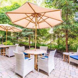 A cozy outdoor patio area with tables and umbrellas surrounded by lush greenery.