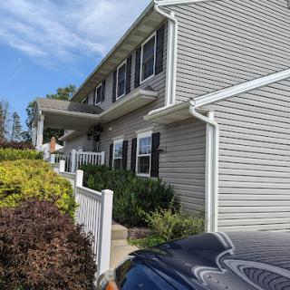 A charming two-story house surrounded by well-kept landscaping under a clear blue sky.