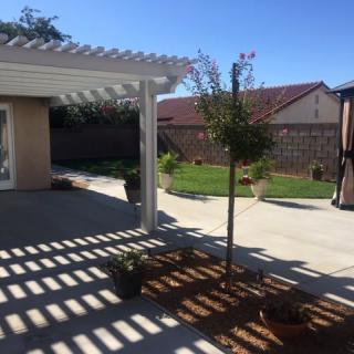 A sunny backyard with a pergola and garden.