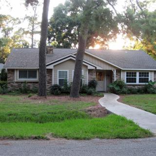 A suburban house surrounded by trees with a neatly maintained lawn and pathway.