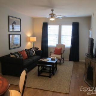 A cozy living room with a sofa, coffee table, and a ceiling fan.