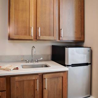 A compact kitchen area with wooden cabinets, a sink, and a small refrigerator.