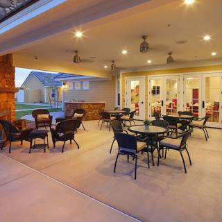 A cozy outdoor patio area with tables and chairs under warm lighting, offering a comfortable space for dining or gatherings.