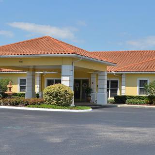 A building with a covered entrance and landscaped surroundings under a clear sky.