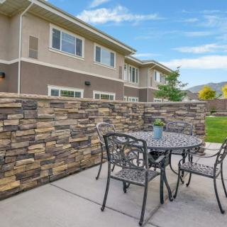 A cozy patio area with a stone wall, featuring a small table and four chairs, located outside a residential building.