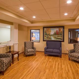 A cozy seating area with armchairs and a sofa, featuring a landscape painting on the wall.