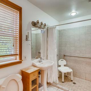 A well-equipped accessible bathroom with a shower chair and tiled walls.