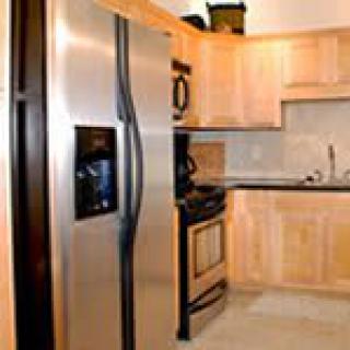 A modern kitchen featuring stainless steel appliances and light wood cabinets.