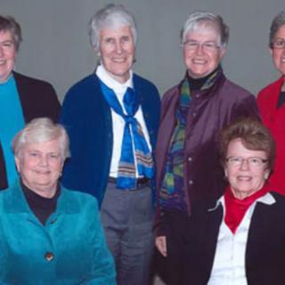 A group of older adults posing for a photo indoors, wearing casual attire and smiling.