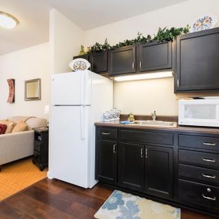 A cozy kitchen area in an apartment with dark cabinets, a refrigerator, and a microwave.