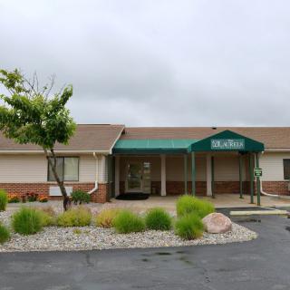 A building with a green awning and landscaped surroundings on an overcast day.