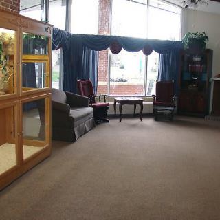 A spacious lobby area featuring chairs, an aquarium, large windows with curtains, and a carpeted floor.
