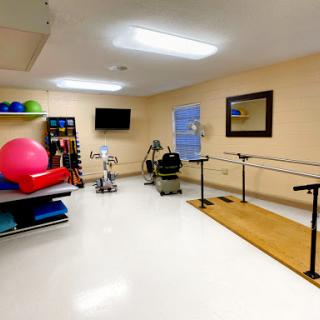 A well-equipped physical therapy room featuring various exercise equipment and a barre for rehabilitation exercises.