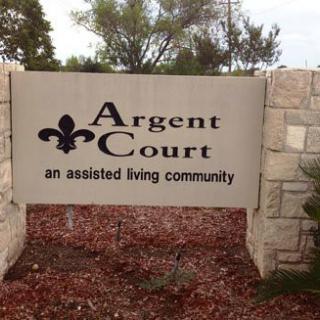 A sign for Argent Court, an assisted living community, set in a landscaped outdoor area.