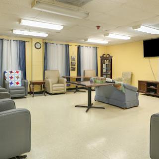 A cozy lounge area featuring comfortable seating, a television, and warm yellow walls, providing a welcoming space for relaxation.