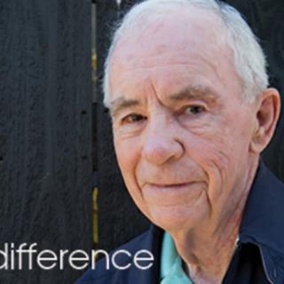 An elderly man posing outdoors in casual clothing.