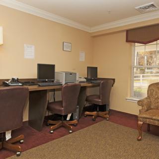 A small office area with computers and chairs along a row of desks by the window.