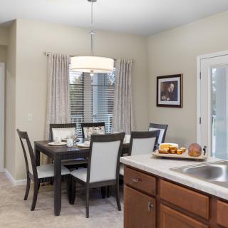 A cozy dining area adjacent to a kitchen, featuring a table set for meals and warm lighting.