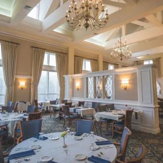 An elegant dining room with chandeliers, large windows, and neatly set tables.