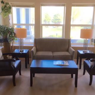 A cozy living room setup with a sofa, chairs, coffee table, and lamps by the windows.